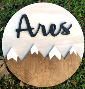 18" round sign featuring three snowcapped mountain designs. Option to choose between painted or stained finish, with the ability to add a custom name above the mountains for a personalized touch."