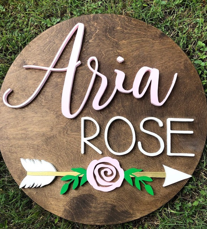 23" round sign showcasing a simple rose design with an arrow beneath it. This versatile and elegant piece can convey a meaningful biblical sentiment or add a touch of boho charm to a girl's room decor."