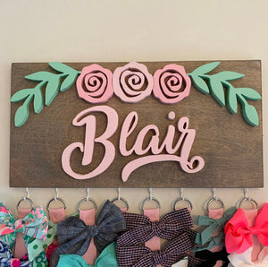 Custom wooden bow holder designed for girls with a rose arch and leaves motif.  Features 8 hooks and. 8 ribbons for organizing bows. Personalized with the individual's name for a unique touch.