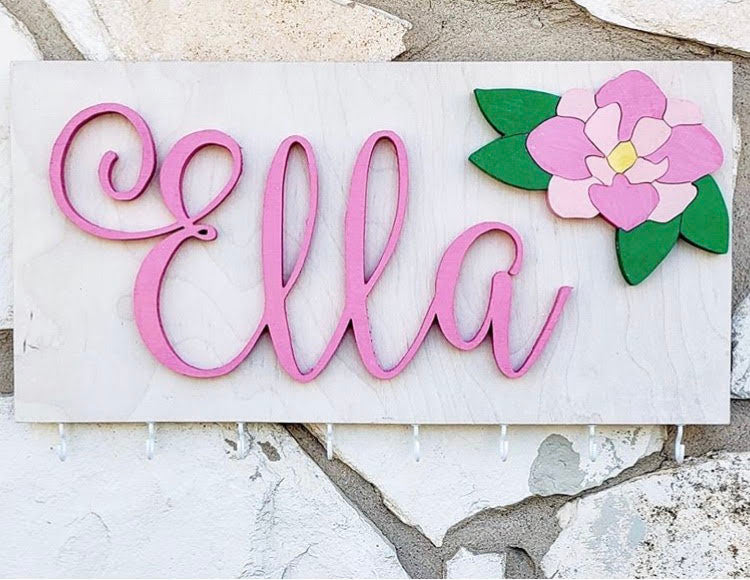 "Charming 16x8 Bow Holder with 8 Hooks, 8 Ribbons, and Lovely Flower Design - Personalize with a Girl's Name for the Perfect Nursery or Girls Room Decor. Ideal Baby Shower or Mom Gift for a Touch of Personalized Elegance." Woodwork Barn