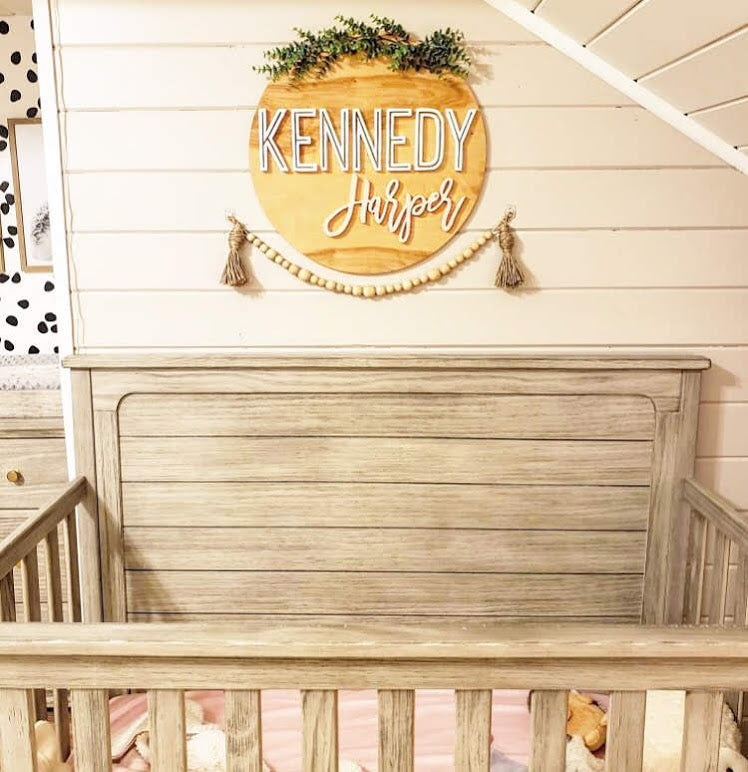 Elegant 20" round sign featuring a simple and timeless design with customizable name. Choose from various stains, fonts, and colors to seamlessly match the theme of your child's room, combining beauty and practicality in one personalized piece.